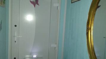 A cozy room with a door featuring a small window and a handle, adorned with a decorative sticker. A framed picture and ornate mirror add to the space.