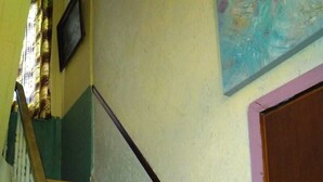 A staircase with wooden steps and white railings, a door with a purple frame, and a wall with a painting. - Room-2 Floors 3 Bedrooms Near Central St (Antwerp)