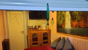 Een kamer met een bed, een houten dressoir, een raam met uitzicht op een waterval en een deur met een kalender.