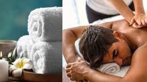 A spa setting with a massage table, a statue, candles, and a tray with various items. - Dream Day Cottages (Kampala)