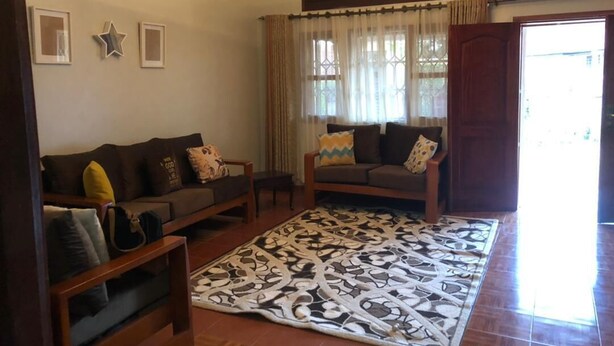 A living room with two sofas, a patterned rug, and a chandelier. - Dream Day Cottages (Kampala)