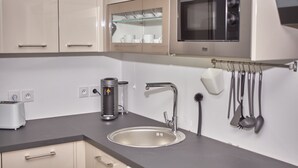 Una cocina moderna con microondas integrado, pileta de acero inoxidable y cafetera.