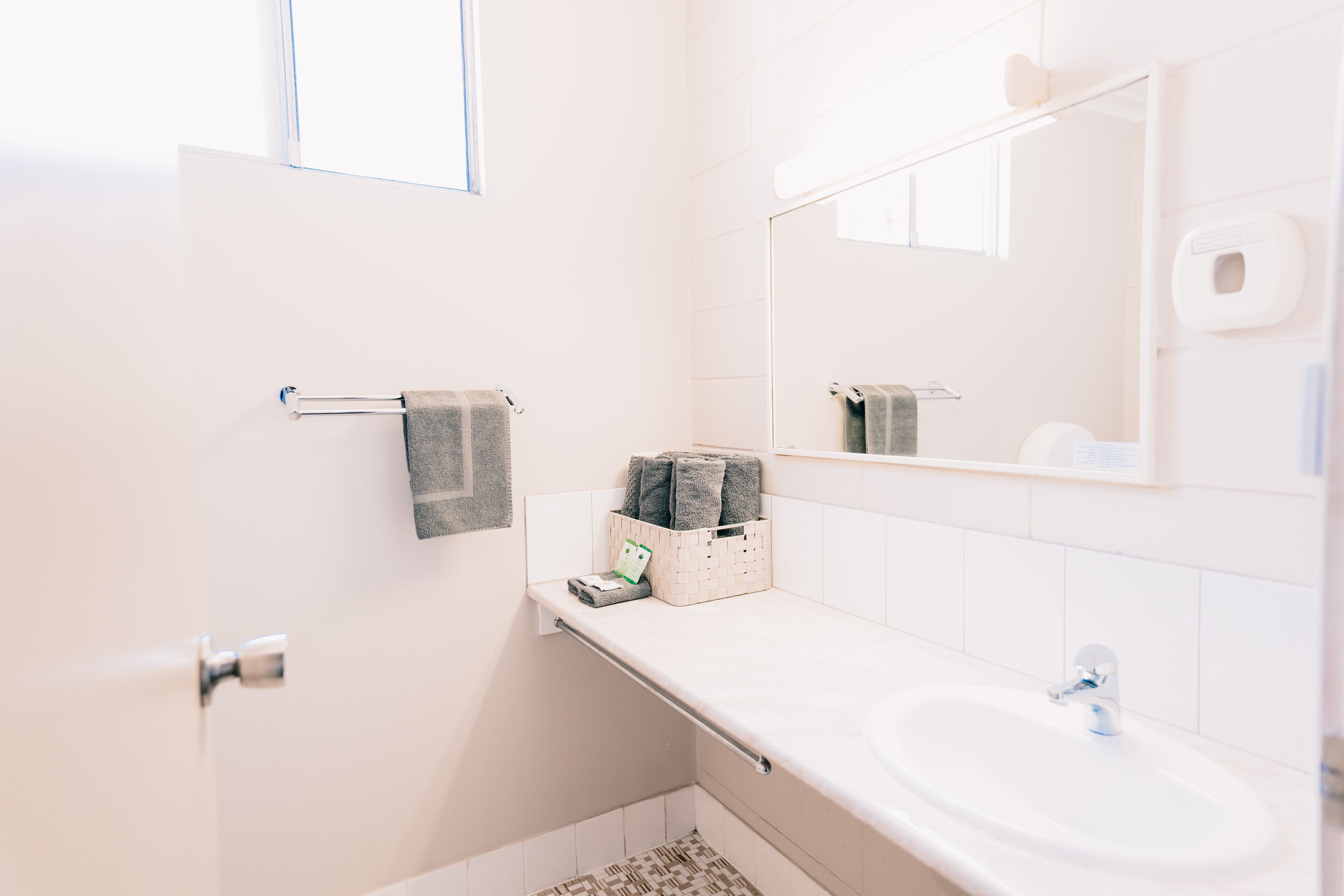 A bathroom with a white sink, a towel rack, a mirror, and a window.