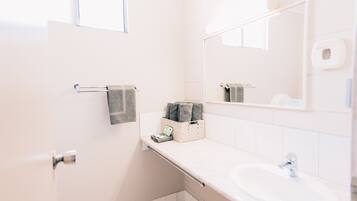 A bathroom with a white sink, a towel rack, a mirror, and a window.