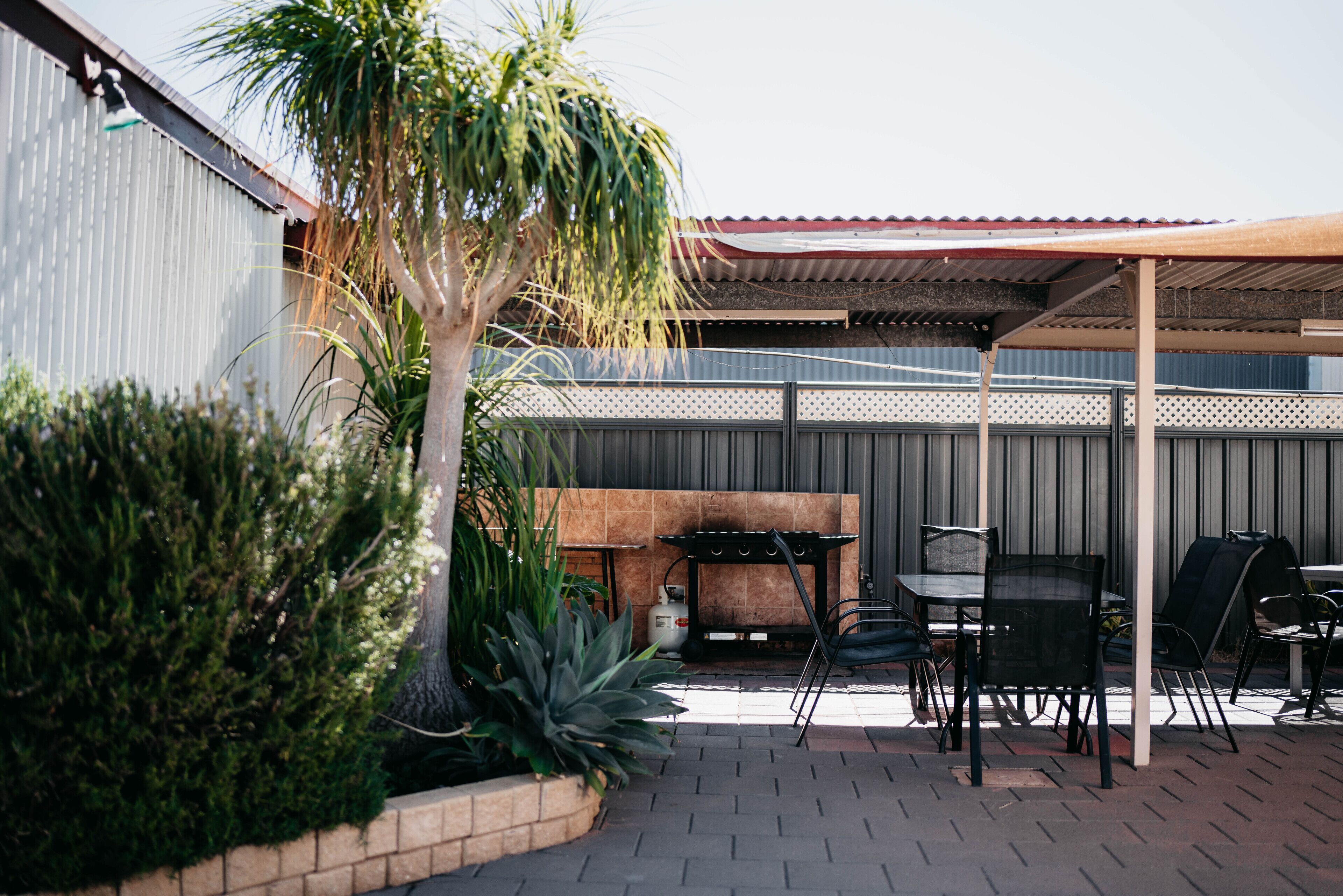 Un espace extérieur aménagé avec un patio, un barbecue, des sièges et des plantes.