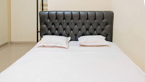 A bed with a tufted headboard, two pillows, and a plain white bedspread. - Hotel O Rinjani Guest House (Balikpapan)