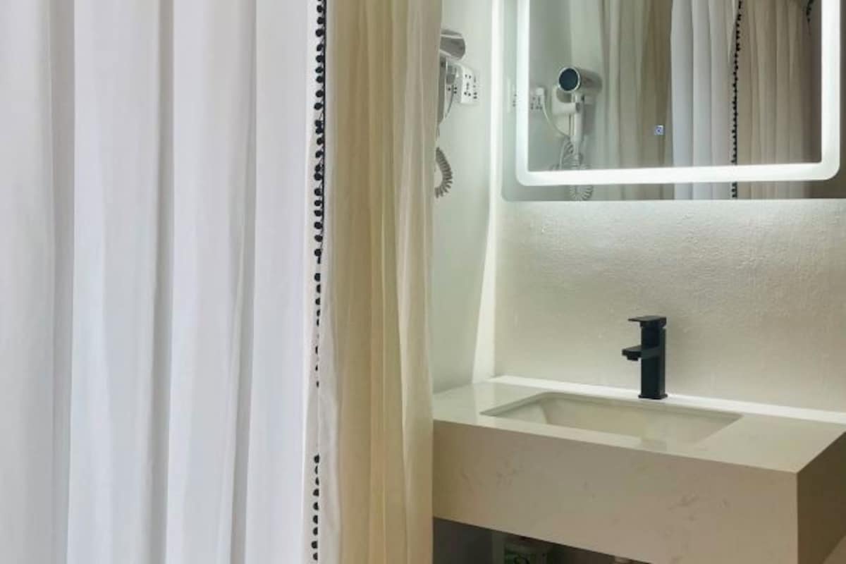 A bathroom with a white sink, a black faucet, and a mirror above the sink.