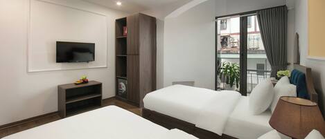 A hotel room with two beds, a TV, a bookshelf, a window with curtains, and a lamp.