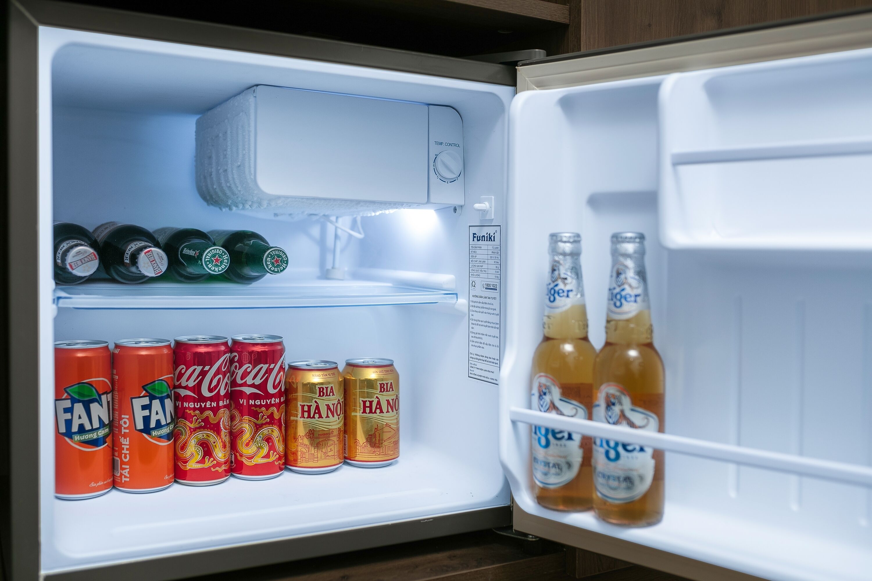 Een open koelkast met verschillende drankjes, waaronder blikjes en flessen.