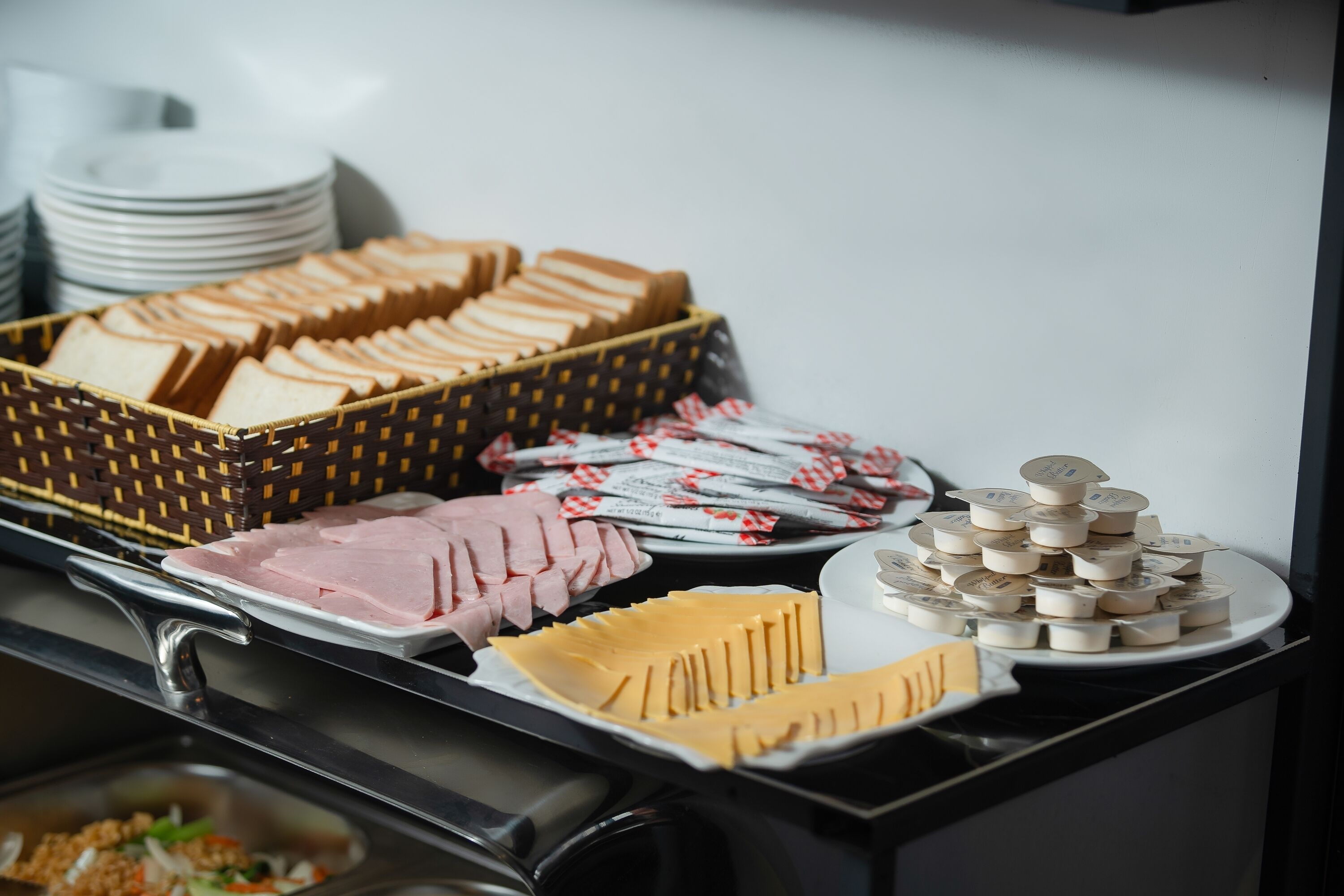 Een buffet met diverse gerechten, waaronder brood, vleeswaren, kaas en toevoegingen.