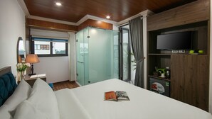 Habitación de hotel con cama, televisor, armario y ventana con cortinas.