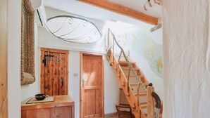 A wooden staircase with a rope handrail, a wooden door, and a wall-mounted air conditioning unit.