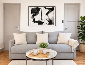 A living room with a grey sofa, a coffee table, and a framed abstract painting.