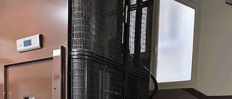 Una escalera con barandilla metálica, una puerta marrón y un ventanal con vidrio esmerilado.