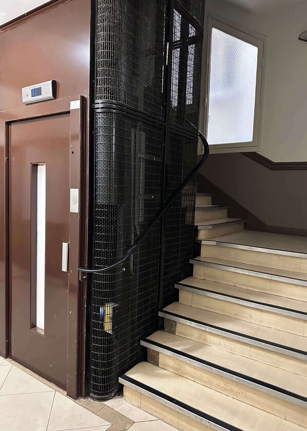 A staircase with a metal railing, a brown door, and a window with frosted glass.