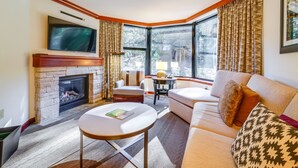 A cozy living room with a fireplace, a comfortable sofa, a television mounted above the fireplace, and large windows with curtains. - Breathtaking Olympic Valley Gem: Walk to Chairlift (Olympic Valley)
