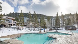 A swimming pool with a stone deck, surrounded by snow-covered ground and trees. - Breathtaking Olympic Valley Gem: Walk to Chairlift (Olympic Valley)
