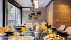 A breakfast setting with a glass table, plates, bowls, and glasses of orange juice. - Luxury Polanco Apt w/ Wine Cellar & Views (Ciudad de México)