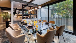 A modern dining area with a glass table, cushioned chairs, and a view of the outdoors. - Luxury Polanco Apt w/ Wine Cellar & Views (Ciudad de México)