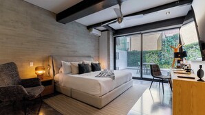 A modern bedroom with a large bed, a desk, a chair, and a view of greenery outside. - Luxury Polanco Apt w/ Wine Cellar & Views (Ciudad de México)