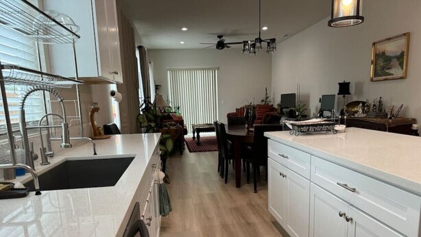Cocina moderna con armarios blancos, horno empotrado y comedor con mesa y sillas.