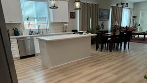 Una cocina moderna con armarios blancos, una isla central y un comedor con mesa y sillas.