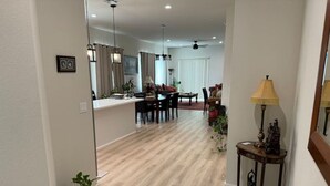 Una sala de estar moderna con suelo de madera, una zona de comedor con mesa y sillas, y una cocina al fondo.