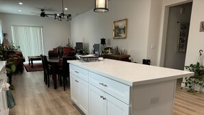 Una cocina moderna con armarios blancos, una isla central y un comedor con mesa y sillas.