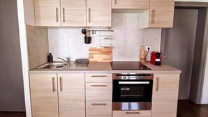 A modern kitchen with light wood cabinets, a stainless steel oven, and a black dishwasher. - le 31 - Mulhouse Pfastatt (Pfastatt)