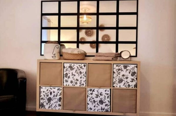 A room with a wooden console table featuring floral-patterned tiles and a black and white abstract artwork.