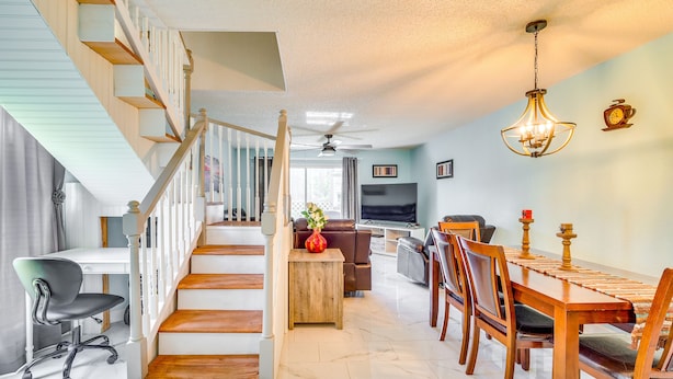 A spacious living area with a wooden staircase, a dining table, and a TV in the background. - Waterfront Inverness Retreat w/ 3 Boat Ramps (Inverness)
