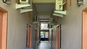 A corridor with multiple doors, air conditioning units, and a tiled floor. - Hotel O Mely Homestay (Kendari)