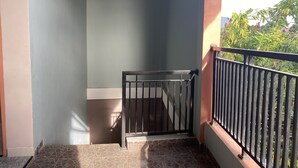 A balcony with a metal railing, a tiled floor, and a light blue wall. - Hotel O Mely Homestay (Kendari)