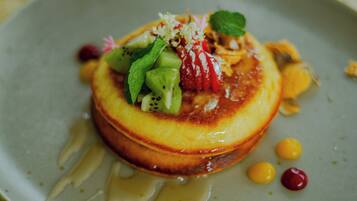 A dessert on a plate with a drizzle of sauce and garnishes.