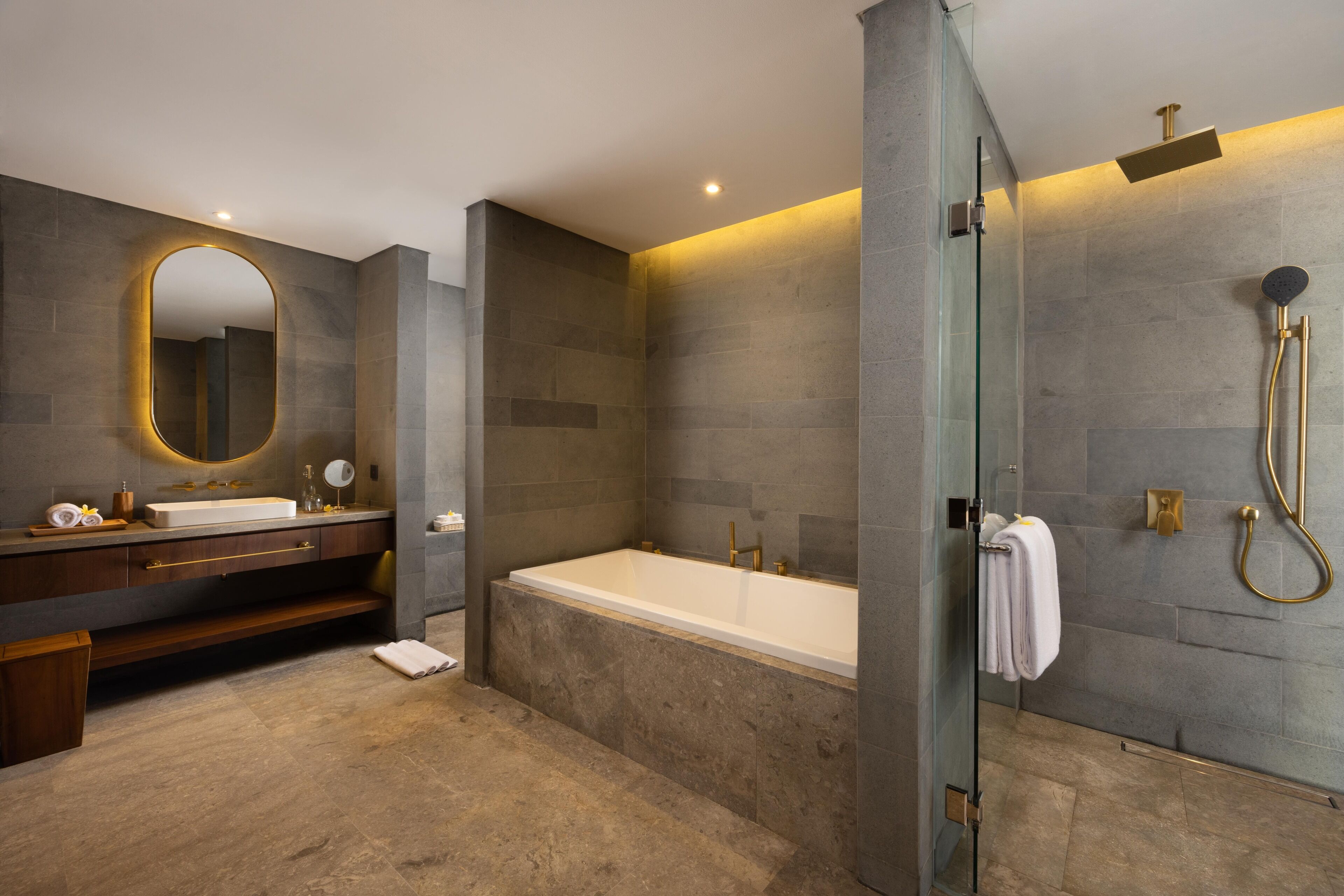 A modern bathroom with a large bathtub, a glass-enclosed shower, and a vanity with a mirror.