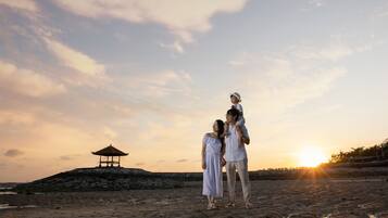 A beach scene with a gazebo, a sunset, and a family.