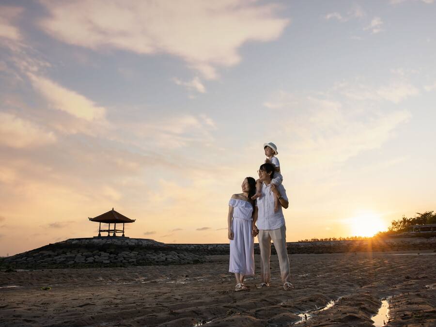 A beach scene with a gazebo, a sunset, and a family.