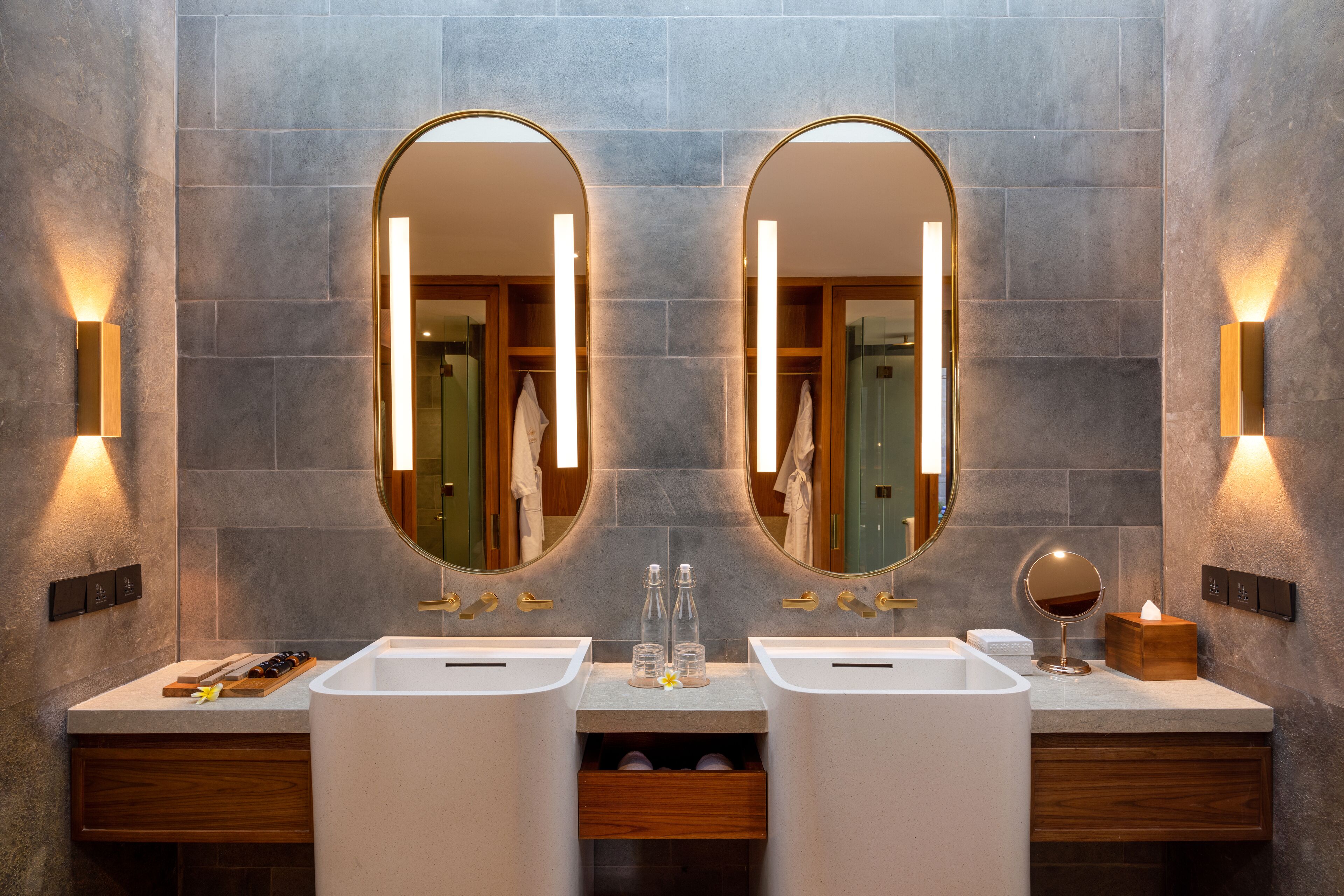 A modern bathroom with two sinks, a large mirror, and wall-mounted lights.