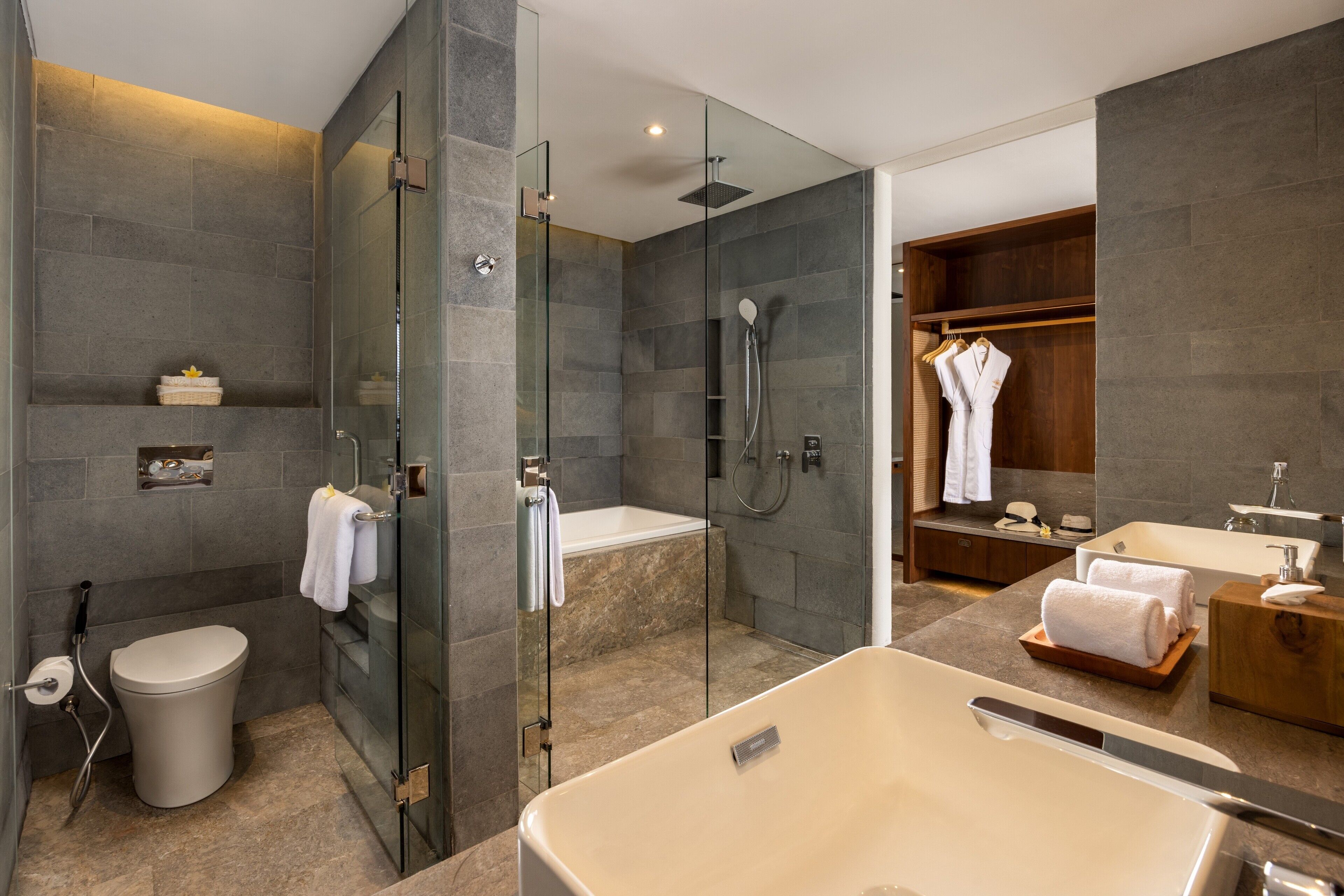 A modern bathroom with a glass-enclosed shower, a freestanding bathtub, a toilet, and a vanity with a sink and mirror.