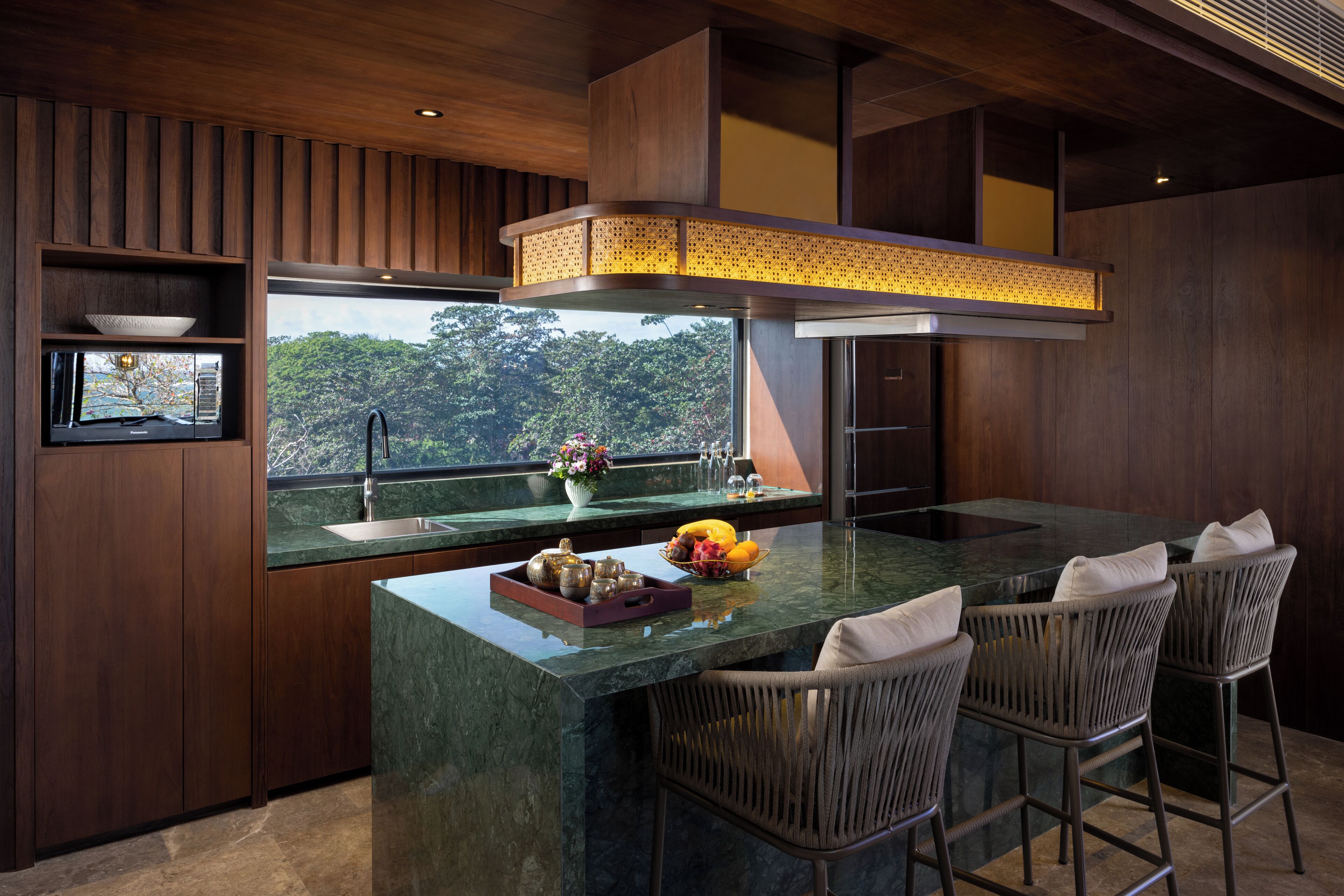 A modern kitchen with a large island, bar stools, and a view of the outdoors.