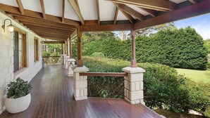 Eine überdachte Veranda mit Holzbalken und Säulen, die zu einem üppigen, grünen Garten führt.