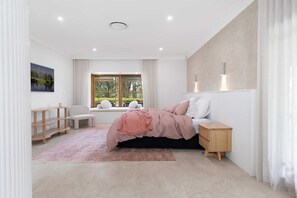 A bedroom with a bed, bedside table, nightstand, and a window with curtains.