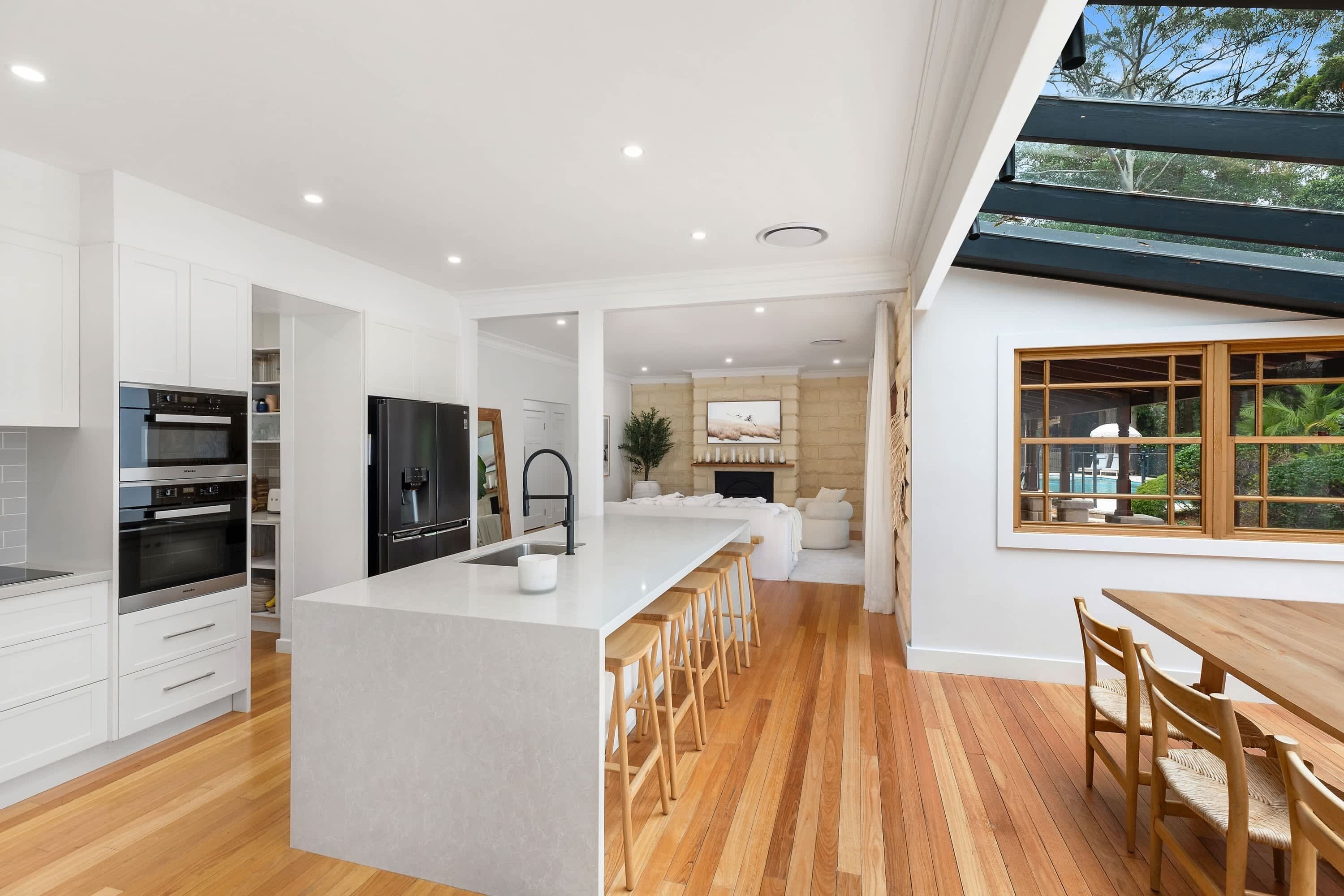 A modern kitchen with white cabinetry, a central island, and wooden flooring.