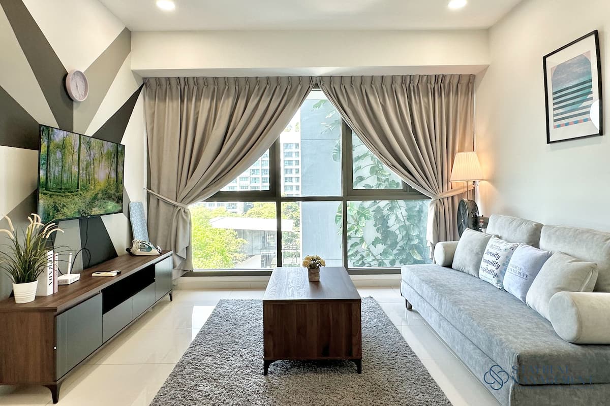 Uma sala de estar moderna com televisão de tela plana, mesa de centro de madeira, sofá cinza e uma janela grande com cortinas.