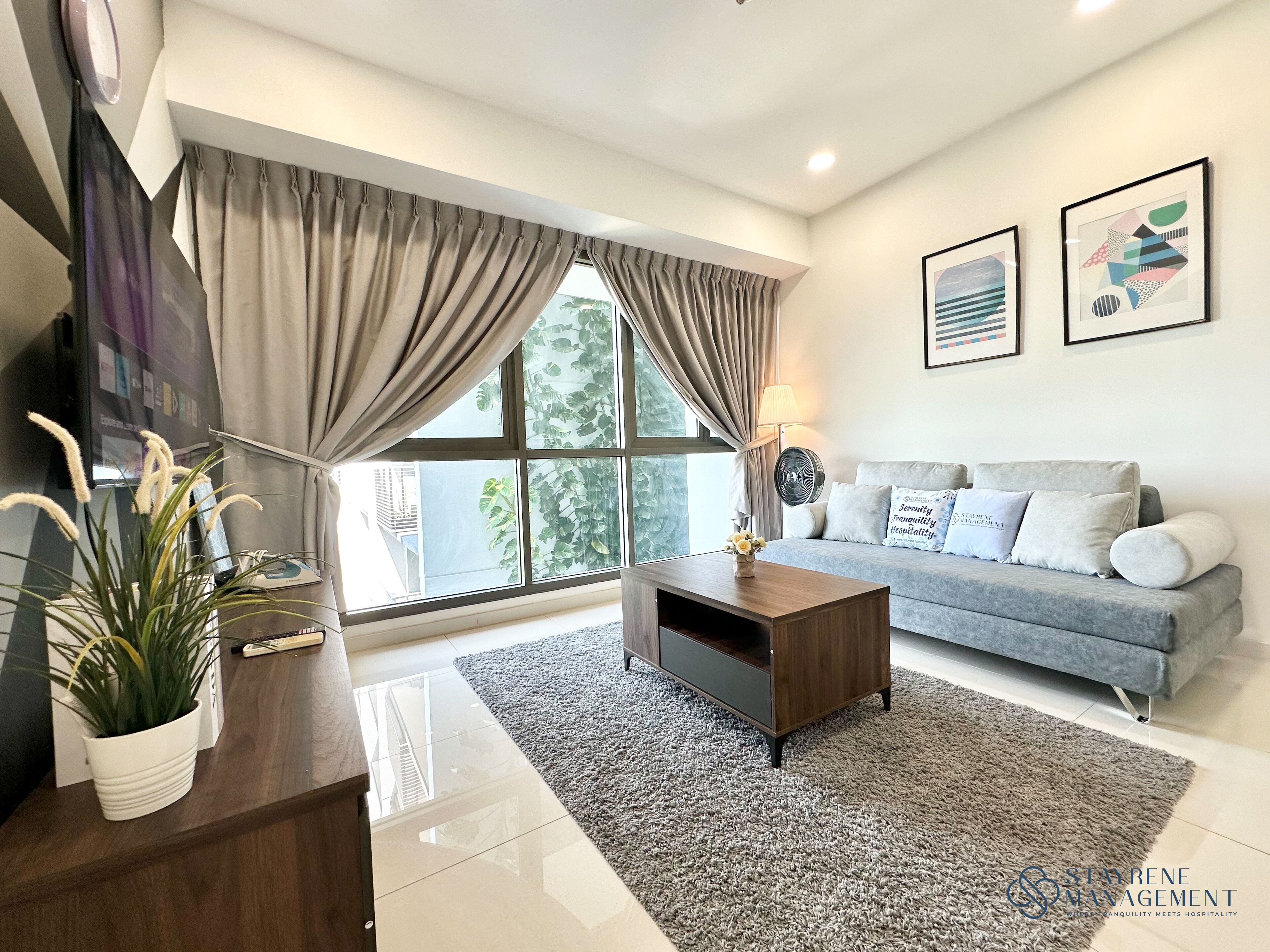 A modern living room with a grey sofa, a wooden coffee table, and a large window with curtains.