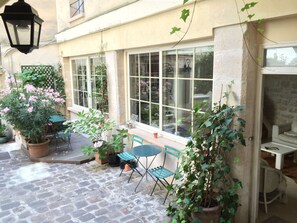 A courtyard with stone flooring, potted plants, and outdoor seating. - Duplex (ground floor and 1st floor - 2 bedrooms 2 bathrooms) -Center- Le Marais (Paris)