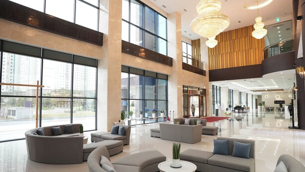 Un hall d’entrée spacieux, doté de grandes fenêtres, de meubles modernes et d’un lustre.