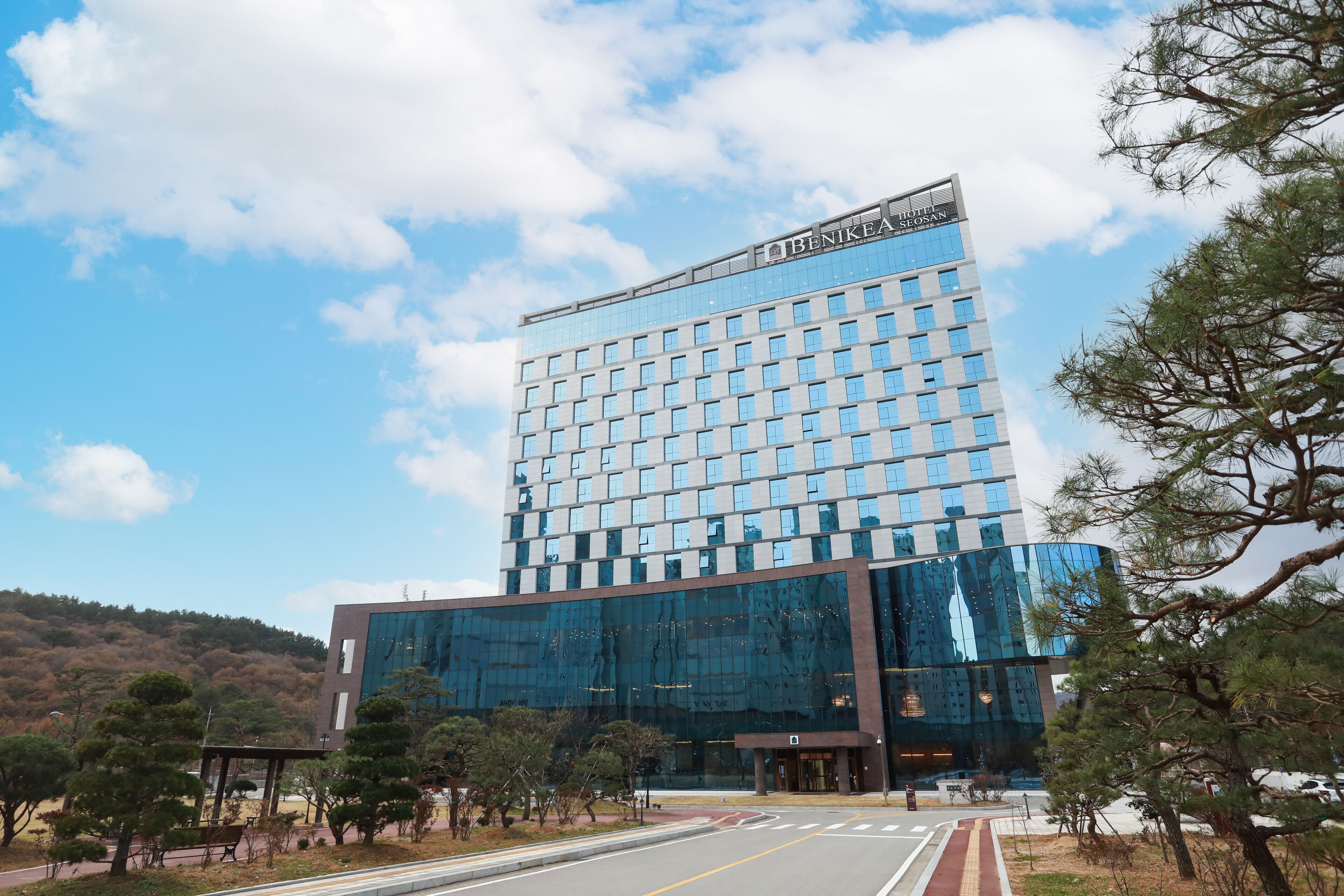 A modern hotel with a glass facade, multiple floors, and a prominent sign at the top.