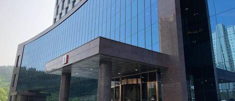 Un edificio moderno con fachada de vidrio y un área de entrada cubierta con columnas.