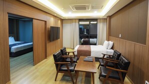 Une chambre d’hôtel avec un lit, un bureau, deux chaises et un téléviseur.
